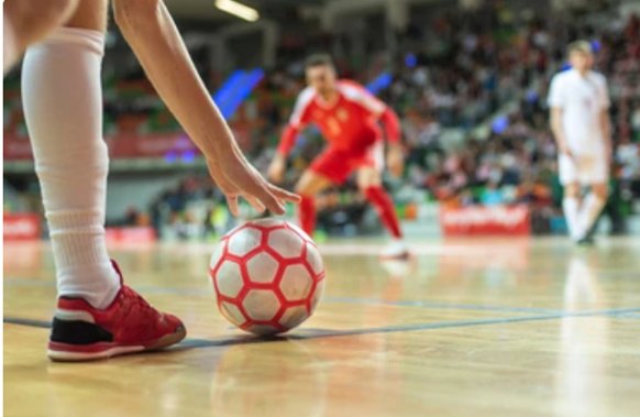 A young futsal player about to play the ball during an indoor futsal match